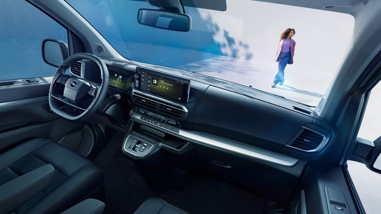 Interieur van een witte Opel Zafira vanaf de passagiersplaats met een vrouw die buiten staat